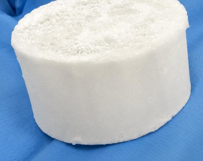 A small white cylinder of super ice (BioPykrete), about two centimetres across, used in compression testing